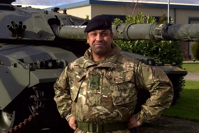 James Cleverly in British Army uniform, standing in front of a Challenger tank