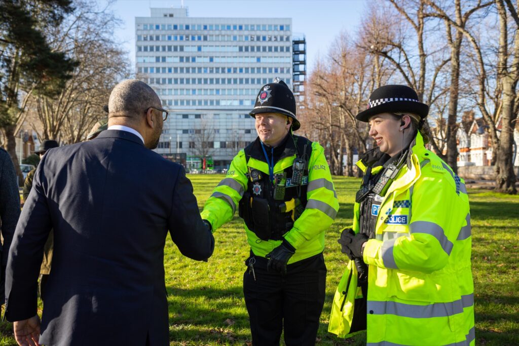 James Cleverly shaking hands with two Metropolitan Police officers in a London park